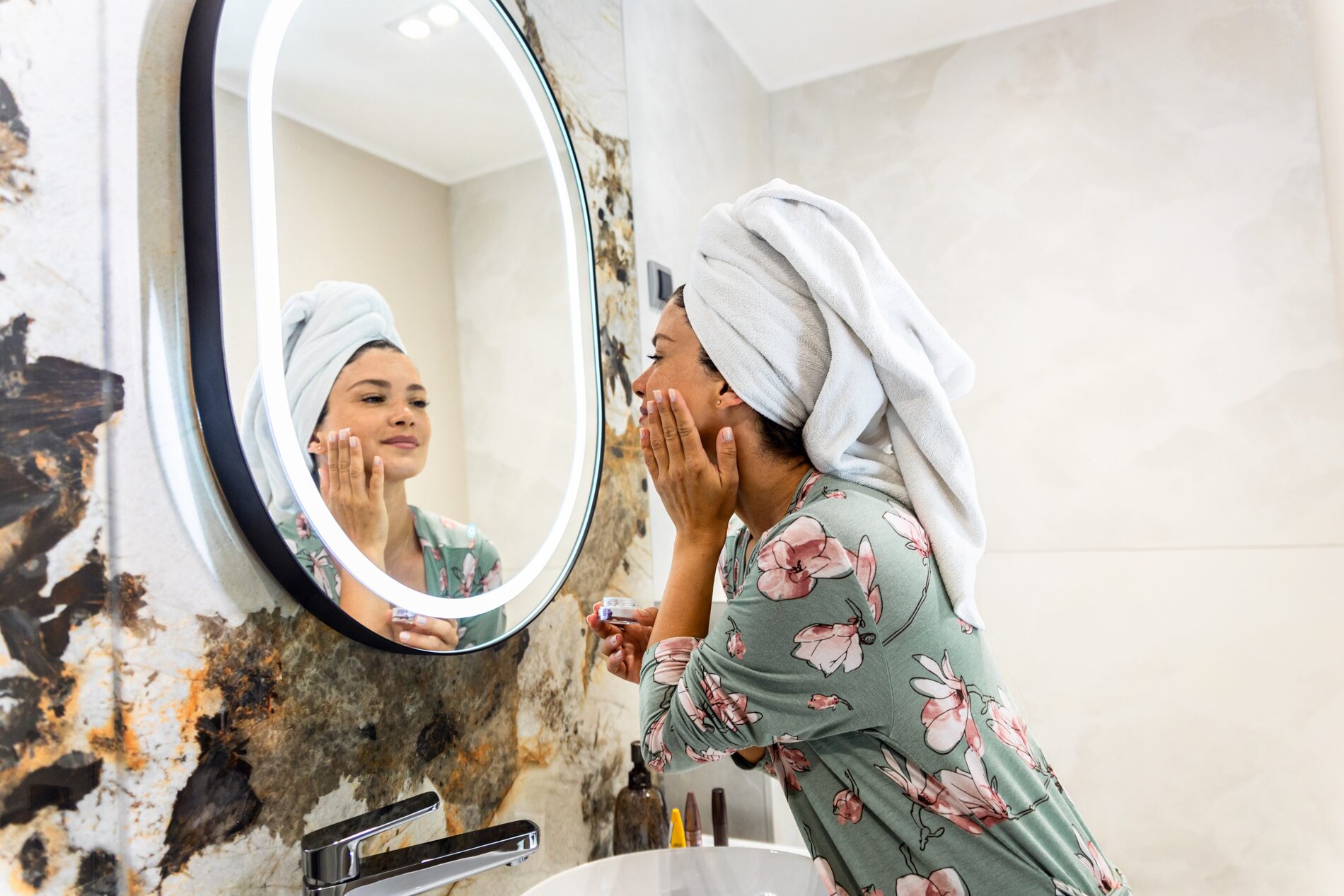 smiling woman applies facial cream in her bathroom 2025 01 29 07 52 33 utc scaled